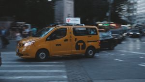 a yellow taxi cab driving down a street next to tall buildings