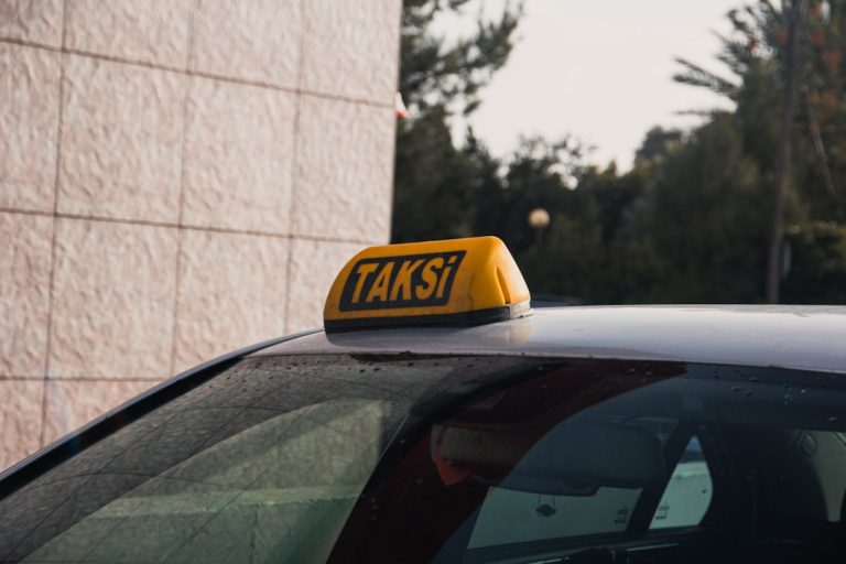 Yellow taxi sign on a car roof.