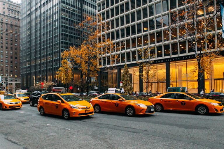 yellow taxi cab on road near high rise buildings during daytime
